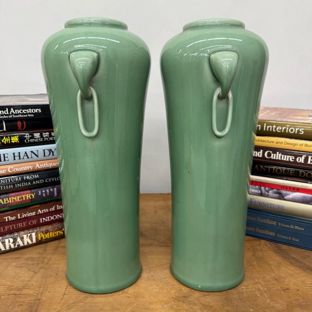 "About This Piece About This Piece This refined pair of green vases carries both elegance and symbolism, their tall,...
