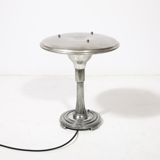 This Art Deco Machine Age saucer-form table lamp, crafted in polished aluminum with a sculptural base and originating from...