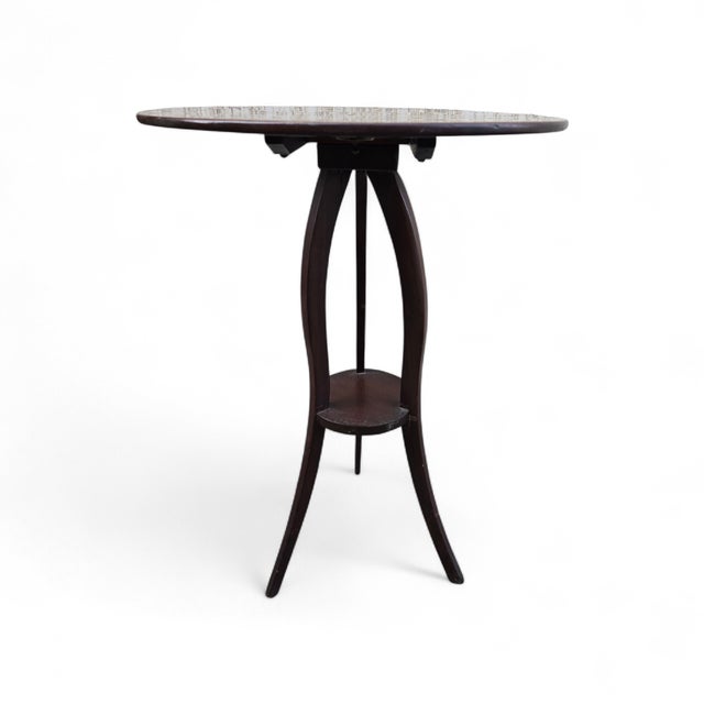 An elegant antique mahogany side table resting on a slender, slightly curved tripod base. This type of side table, highly...