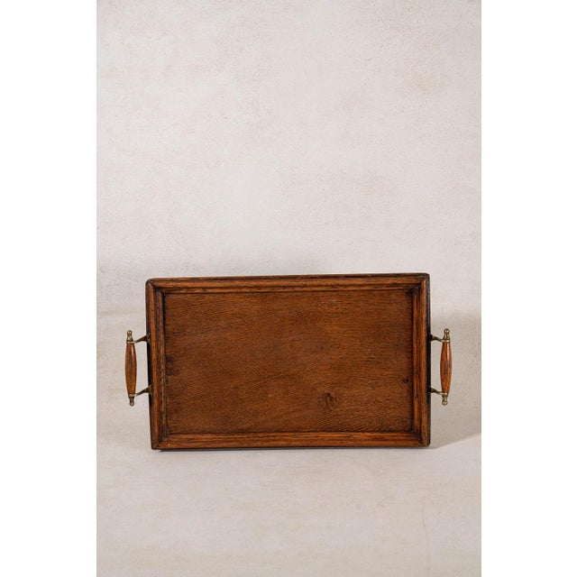 Vintage English oak serving tray with integrated handles, brass corner accents, and a rich aged finish. A functional piece...