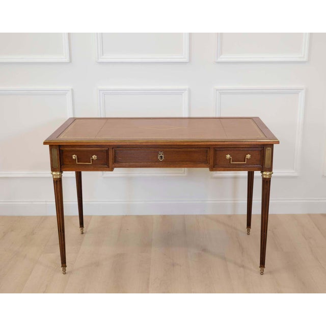 Made in France in the twentieth century, this Louis XVI style flat desk is constructed in wood, with two pull-out slides...