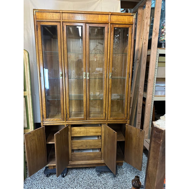 This is a vintage Drexel Heritage Campaign style china cabinet from the Accolade Collection. It features a medium-tone...