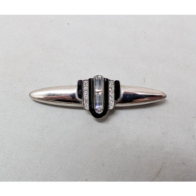 1980s Art Deco style rhodium plated U of black enamel with two clear baguette rhinestones in the center with a line of...
