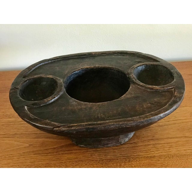 A carved wood platter with three concave dishes on a raised foot. The utilitarian form takes on sculptural qualities with...