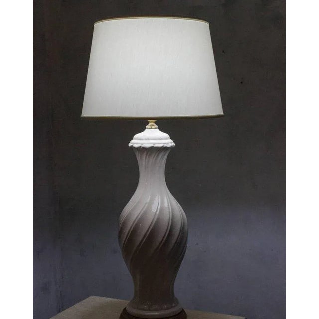 A sculptural Spanish Mid-Century table lamp from the 1950s, featuring a gracefully formed white ceramic body with a richly...