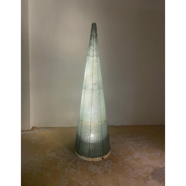 Eric Debras's 1970s floor lamp features a dramatic conical shape reminiscent of a luminous pyramid. The internal metal...
