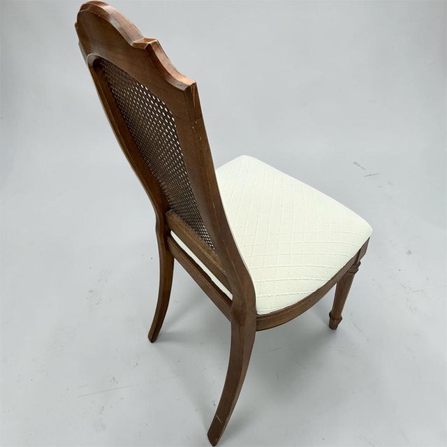 Elegant vintage Drexel dining chair featuring a classic French Provincial silhouette with a beautifully woven cane back,...