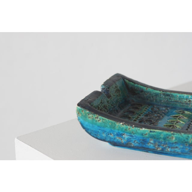 A low vessel with an asymmetrical, shallow form, featuring opposing sections of the rim that are characteristically turned...