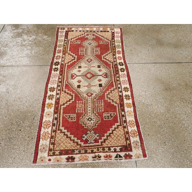 A vintage Turkish Oushak throw rug. A stepped, pendant geometric elongated ivory medallion is set on a red sub-field with...