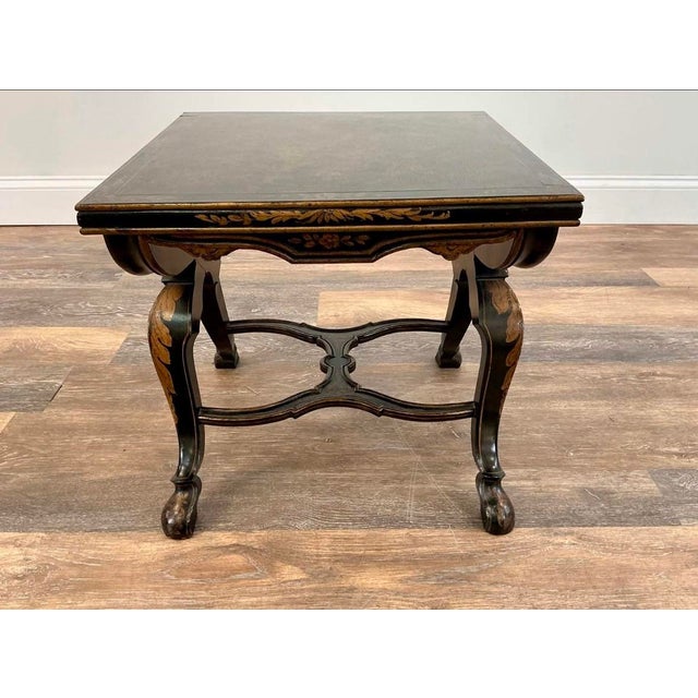A striking pair of low decorative side tables featuring black lacquered finishes with hand-painted gold floral and foliate...