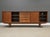 A mid century modern teak credenza with four sliding doors, five drawers, and sculpted pulls designed by Arne Vodder for...