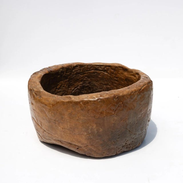 A substantial hand-hewn wooden bowl carved from a single burl section, retaining its irregular form and textured interior....