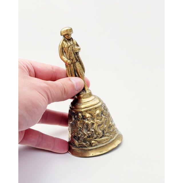 An elegant late 19th-century Belgian cast brass table bell, dating to circa 1890, richly decorated with sculptural relief...