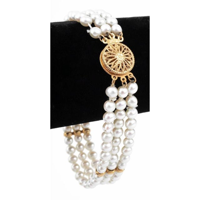 This is a vintage triple-strand pearl bracelet crafted in 14k yellow gold. It features three rows of lustrous pearls...