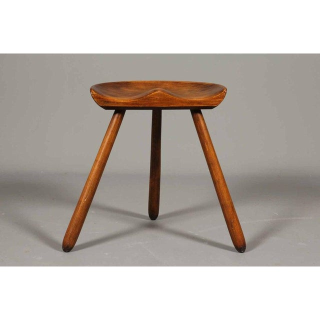 The stool, design by Arne Hovmand-Olsen. Patinated oak stool with semi-circular seat, three round tapered legs. Denmark,...