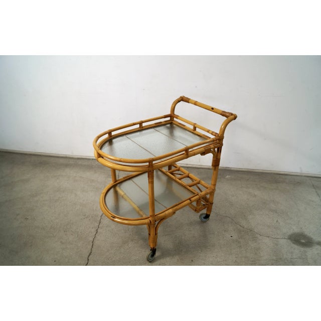 Vintage Midcentury Modern rattan bar cart for sale. Manufactured in the 1960's, and in excellent condition. It has two...