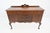 An elegant American Queen Anne Revival walnut sideboard by Baker Furniture, circa 1920s, featuring a gracefully serpentine...
