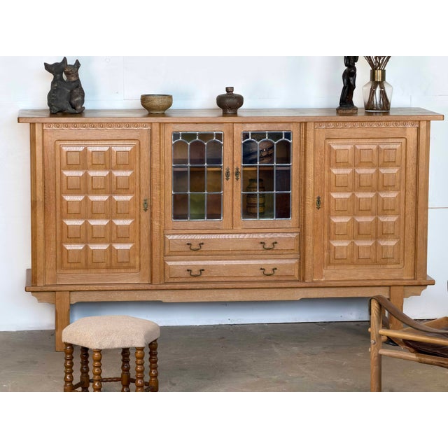 Danish oak sideboard with leaded glass doors, attributed to Henning Kjærnulf, Denmark, 1960s. The case is constructed in...
