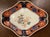 The border of iron red, cobalt blue, and gold surrounds a traditional center featuring a lion-dog and peony motif. The...