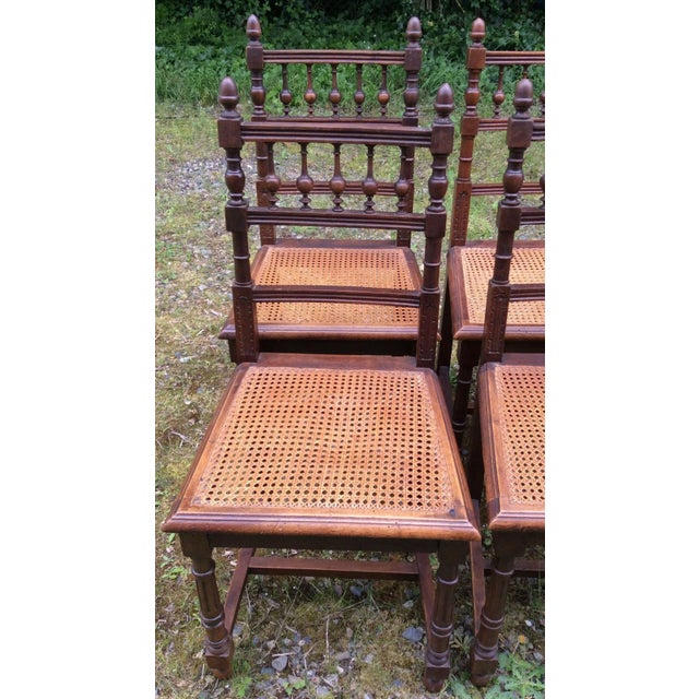 Very classic french dining chairs with spindles, carved columns and cane seats. They have finials on the tops and the legs...