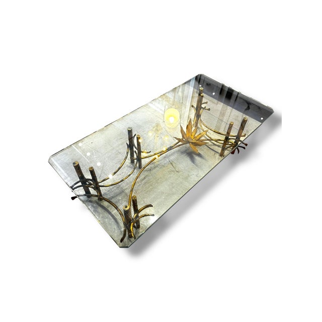 A striking statement piece, this brutalist coffee table features a sculptural metal base designed with organic, branch-...