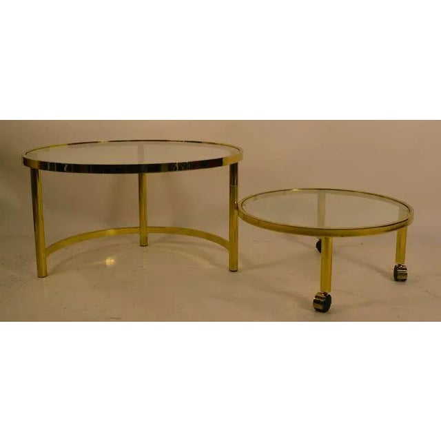 Disk form table which opens to a two tier expanded coffee table size. Brass plated metal frame, with glass tops....