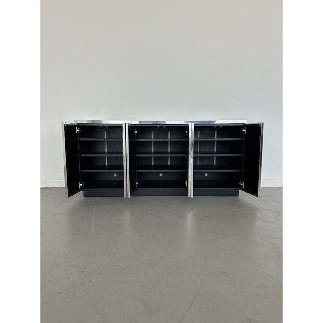 Suavely sophisticated like its namesake, sleek modern console with architecturally inspired details features faux-shagreen...