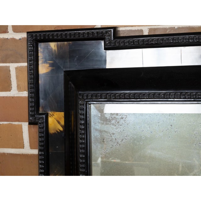 A Dutch faux tortoise black wall mirror from the 19th century with amber accents, carved frame and protruding corners....