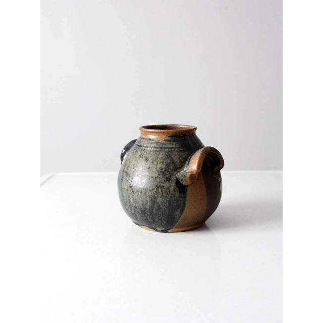 A vintage studio pottery vase, hand-crafted and signed by the artist. The form is defined by a gently rounded body...