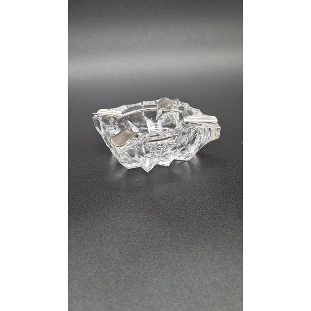 An elegant ashtray made of thick crystal glass with a removable metal rim and four cigarette holders. A classic model with...