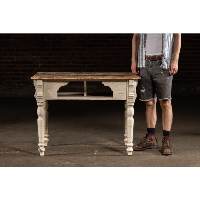A late 19th century farmhouse kitchen table featuring a pine plank top with original distressed finish and a painted base...