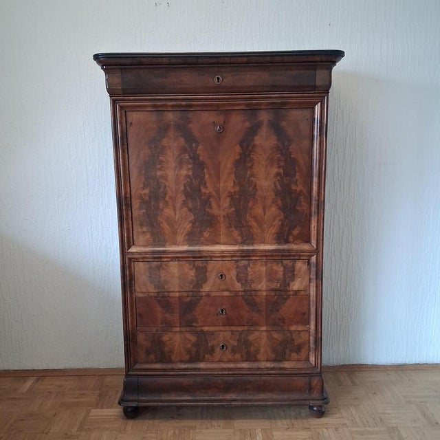 A particularly stylish antique mahogany secretary desk featuring an artfully designed writing surface and a lovingly...