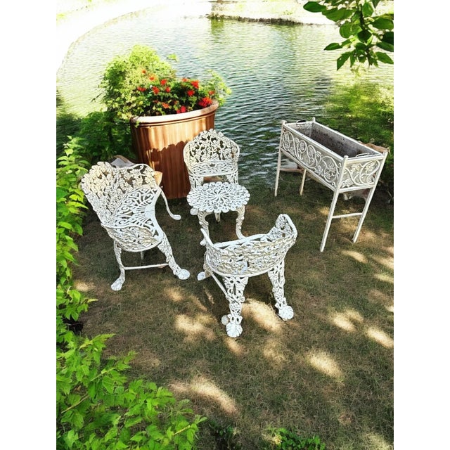 Offering a 5-piece garden set. The settee, two chairs and planter box are heavy cast iron in the early 20th century...