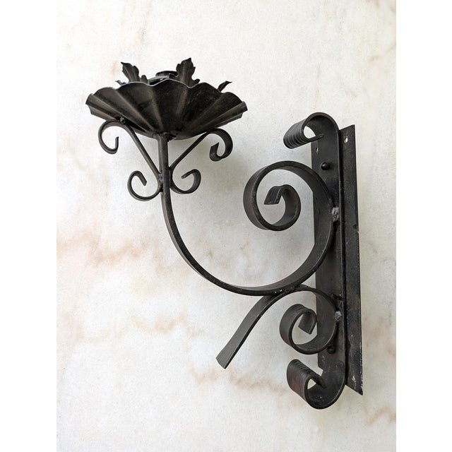 A pair of vintage iron wall-hanging candlestick sconces with floral, leaf and scrollwork design. Weight approx 5lb each.
