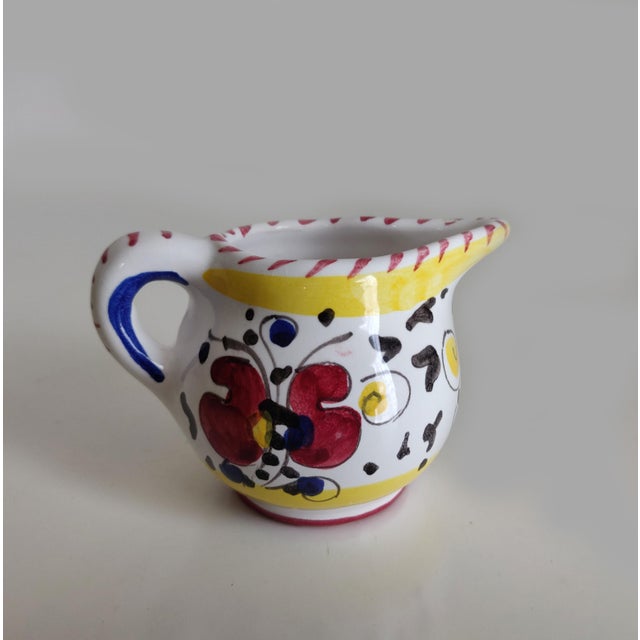 Vintage creamer pitcher A small white ceramic creamer pitcher with a design of yellow, red and blue. The base is stamped...