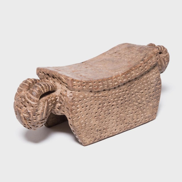 While maintaining the classic stature of traditional Senufo stools, this example radically shifts the form. The solid...