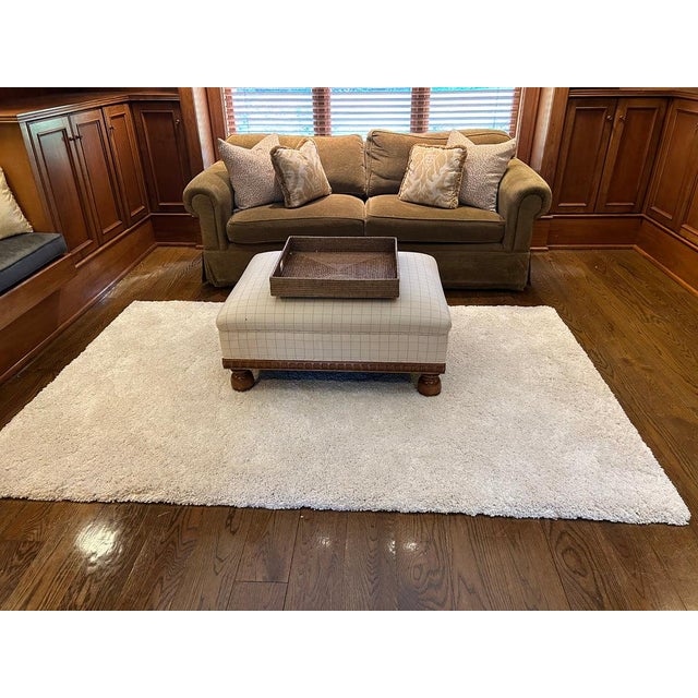 A custom, well-made two-seat sofa with a hardwood frame, classic rolled arms, loose down-filled cushions, and dressmaker...