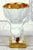 Of sculptural and figurative form, resting on a quadrangular base entirely decorated in gold, the stem is formed as a...