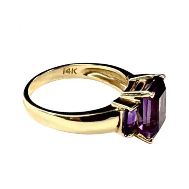 14K Yellow Gold and Amethyst Cocktail Ring. Ring features richly colored emerald-cut amethysts in a three-stone...