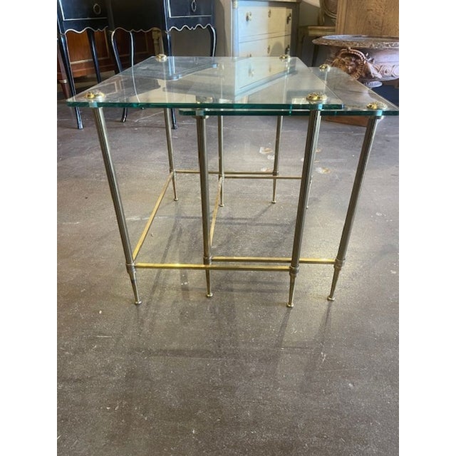 This set of vintage French brass nesting tables with glass tops is perfect for adding a touch of elegance to your home....