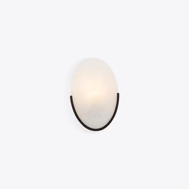 The Mosman Disk Wall Sconce is an oval disc of smooth, naturally grained alabaster. The alabaster shade of this wall light...