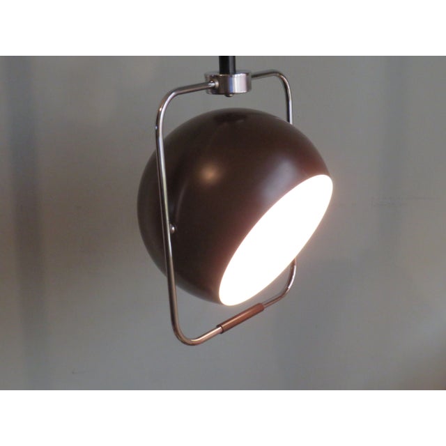 Brown lacquered metal spherical hanging lamp with white lacquered interior in a rectangular chrome frame. The lamp can be...