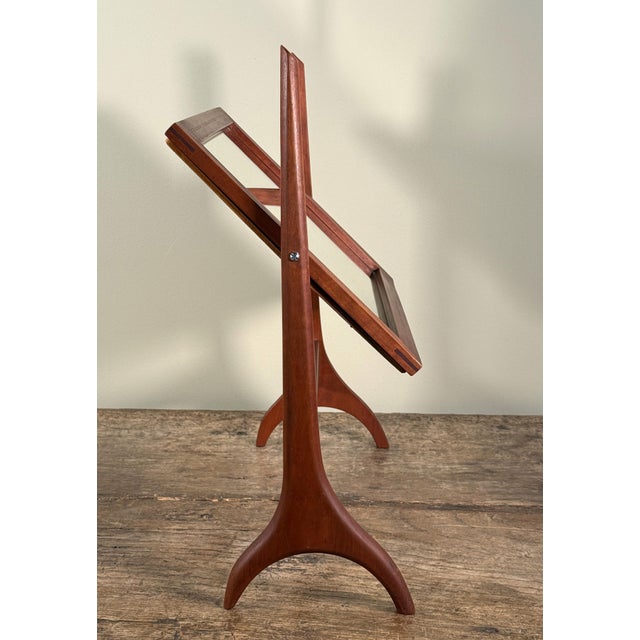 This stunning mid century vanity mirror features a rectangular teak frame supported by a sculptural stand with curved...