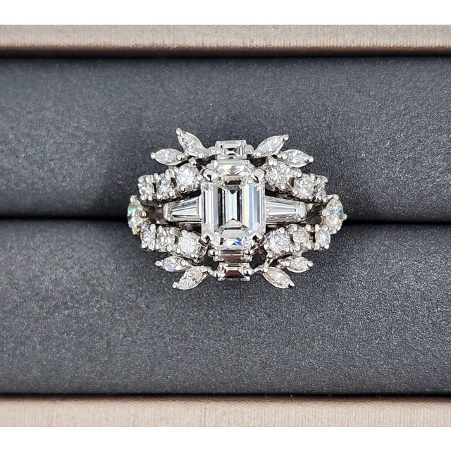 A striking 2.02-carat GIA-certified emerald-cut cornered rectangular step-cut diamond takes center stage, exhibiting a...