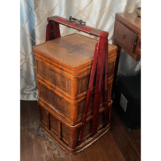 Large Chinese three-tiered vintage tall stacking carrying basket, made of bamboo and rattan with iron handle. Contains...