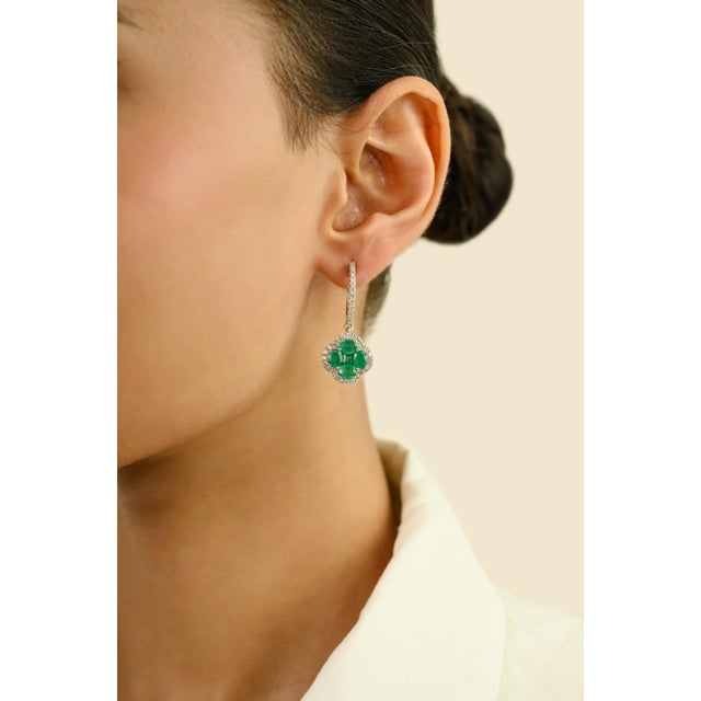 These clover inspired dangle earrings showcase a total of 10 Zambian emeralds weighing 2.92 carats, artfully arranged in a...