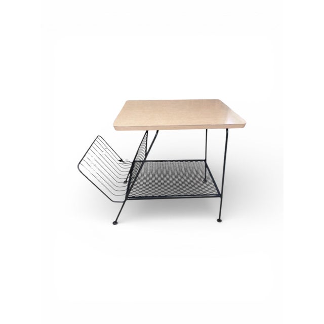 A sculptural and functional mid-century modern magazine rack side table, dating to the late 1950s – early 1960s. This...