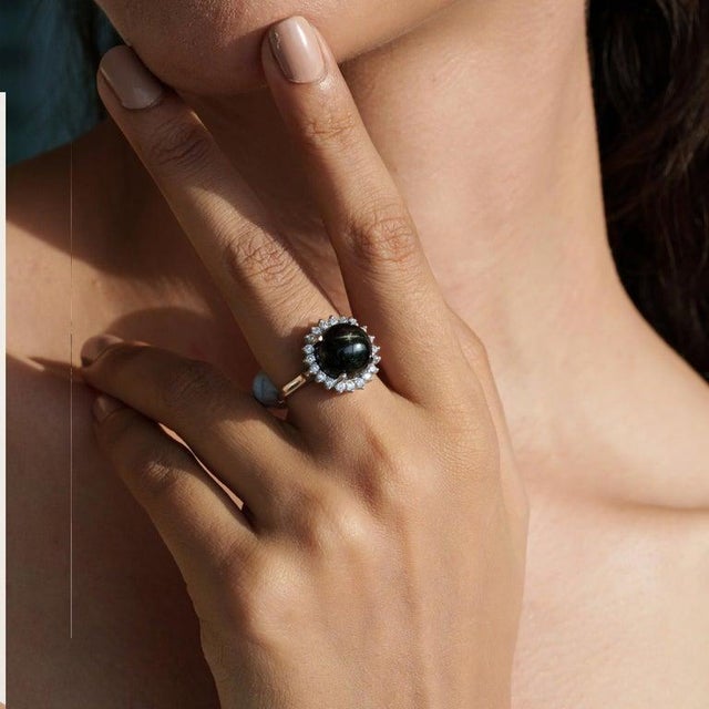 A refined 925 sterling silver cocktail ring featuring a single natural Black Star gemstone in a classic round cut (11 mm,...