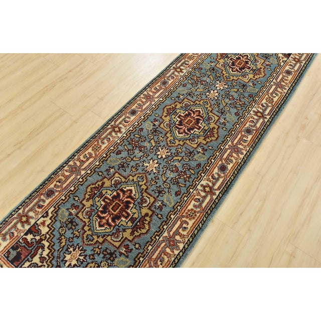 A traditional tribal Heriz runner hand-knotted with an all-wool pile on a cotton foundation. This oriental rug features...