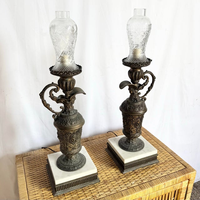 An elegant pair of antique French bronze ewers, later converted into refined oil lamps and topped with finely cut crystal...